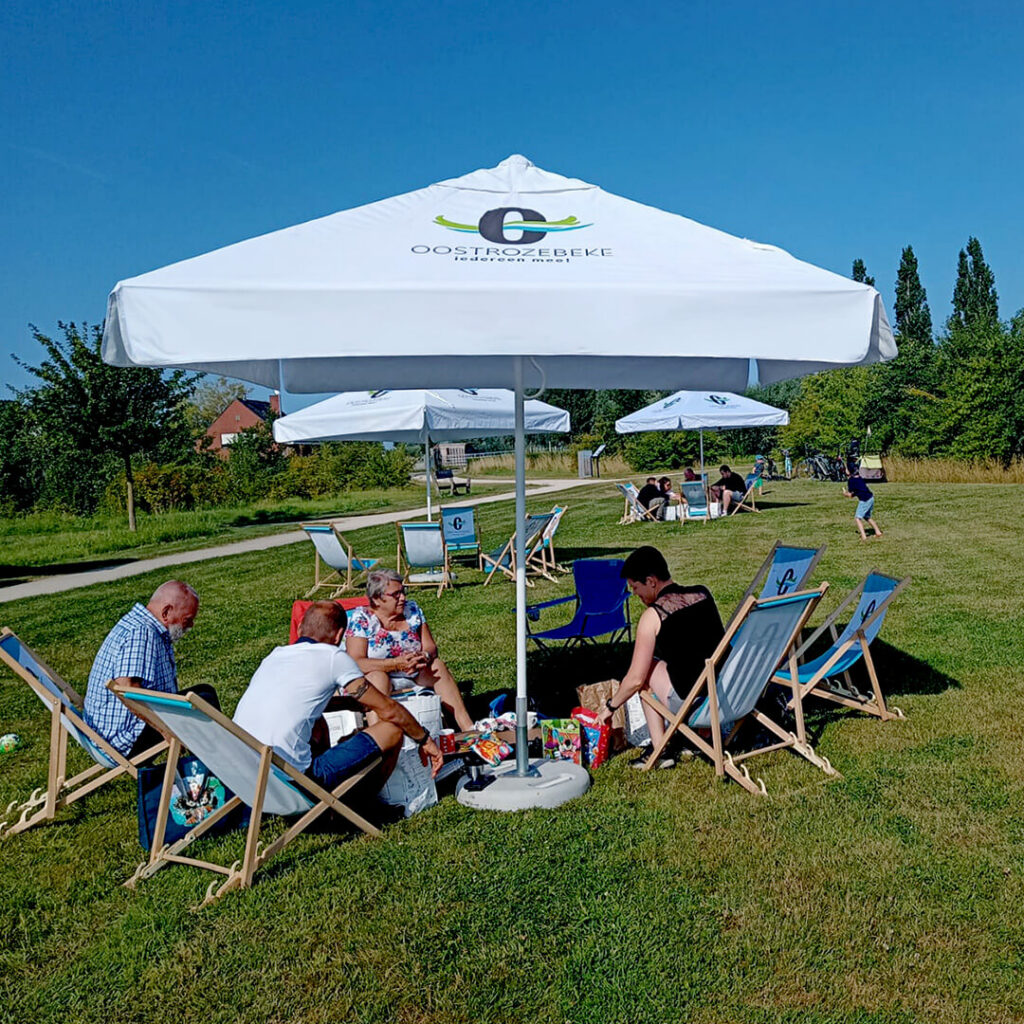 Witte parasol met bedrukking opgesteld buiten op een grasveld